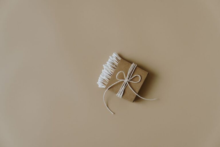 Minimalist design featuring eco-friendly cotton buds wrapped in brown paper on neutral background.